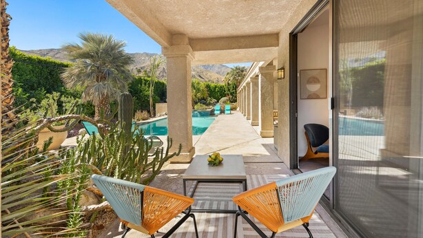 A covered outdoor area with a pool, chairs, and a table.