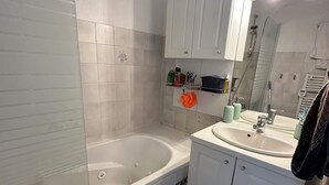 Un baño con bañera, lavamanos y espejo.