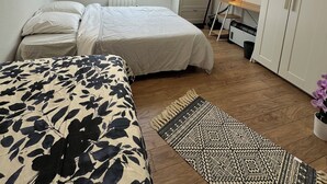 Un dormitorio con cama, escritorio, armario, tragaluz y una alfombra estampada.
