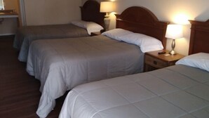 Et hotelværelse med to senge, træsengegavle, sengeborde med lamper samt en trægulv og en loftsvifte.