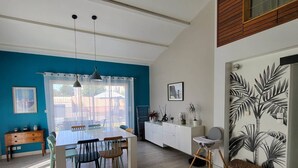 A modern kitchen with a dining area, featuring a large window, wooden cabinets, and a wall-mounted plant. - Villa proche de La Rochelle avec piscine (VILLEDOUX)