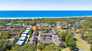 Vista aérea de una zona residencial costera con varias casas y una playa al fondo.