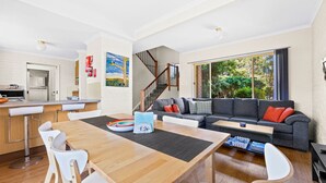 Un espacio habitable moderno con cocina, comedor y un amplio ventanal con vistas al verdor.
