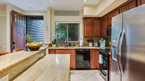 Eine Küche mit Granit-Arbeitsplatten, Holzschränken, Edelstahlgeräten und einem eingebauten Geschirrspüler.