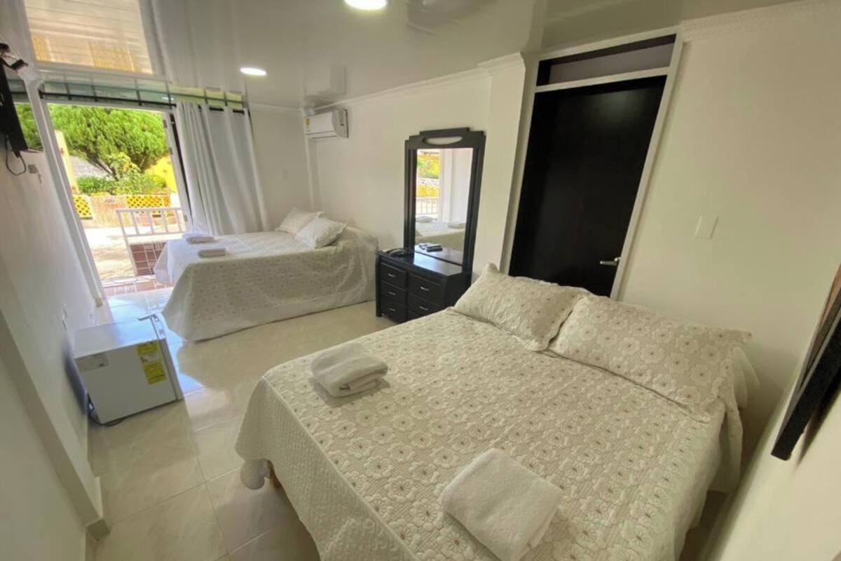 Habitación de hotel con dos camas, una mesita, un espejo y una puerta.