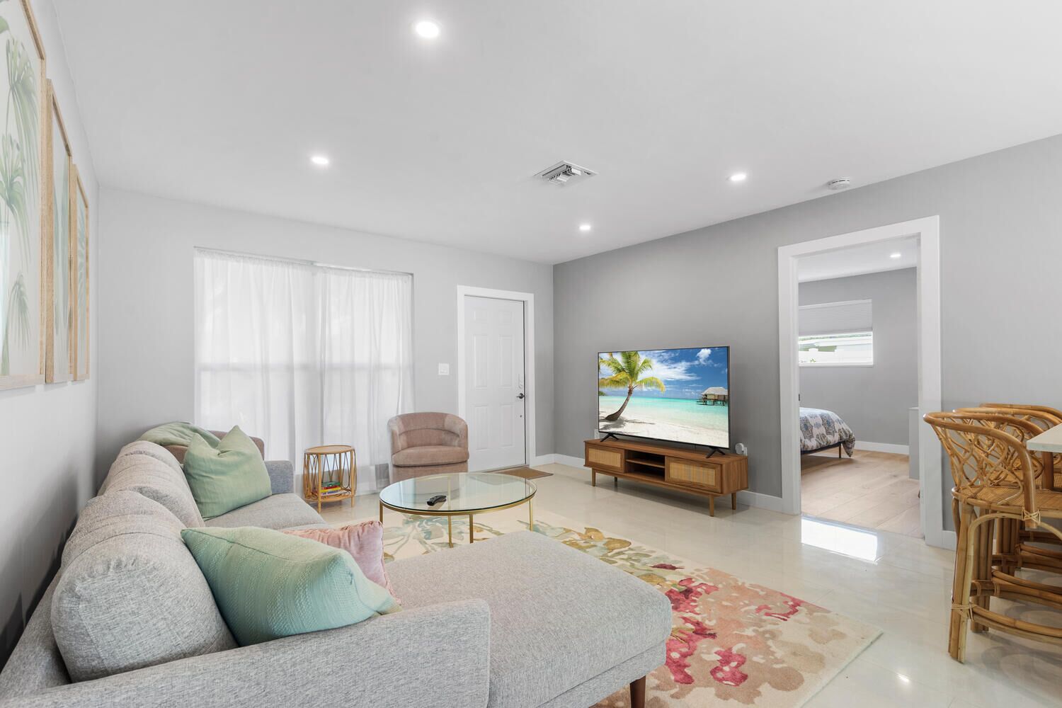 A spacious living room with a sofa, armchairs, a coffee table, and a flat-screen TV.
