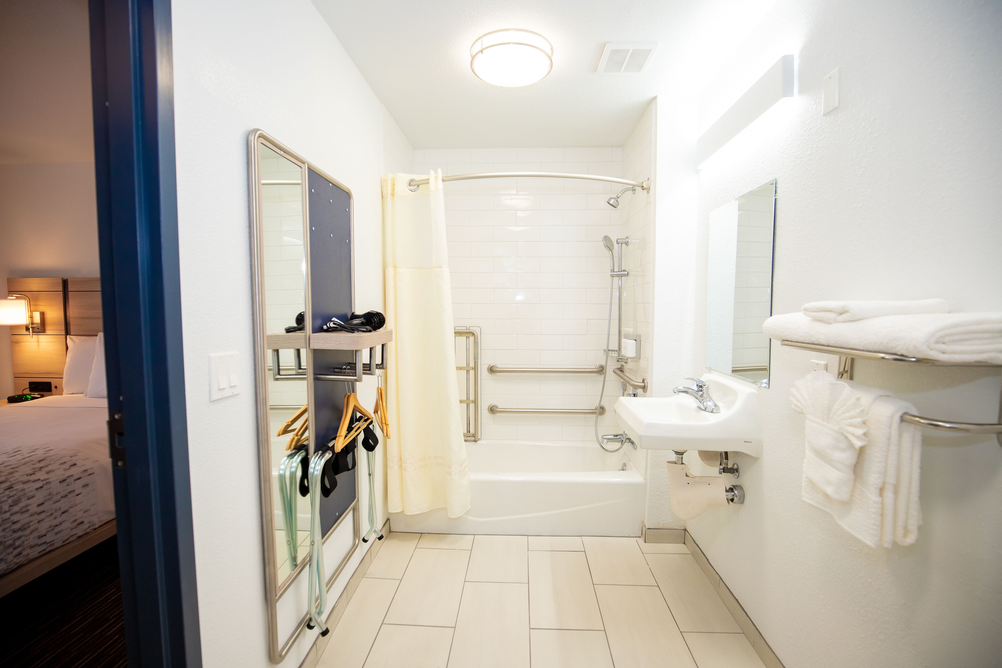 Un baño de hotel con ducha, lavamanos y espejo.