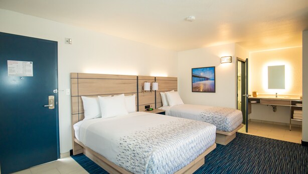 A hotel room with two beds, a bathroom, and a view of a bridge. - Orange Grove Inn (Tustin)