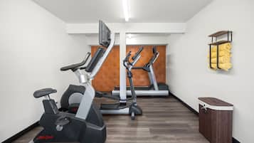 Un gimnasio con dos elípticas, una cinta de correr y un armario de madera.