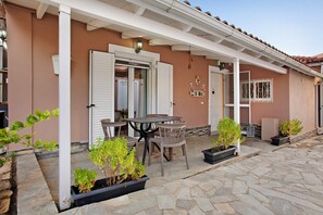 A patio with stone flooring, a table with chairs, and potted plants.