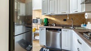 A modern kitchen with white cabinets, stainless steel appliances, and a tiled backsplash.