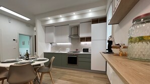Une cuisine moderne avec un coin repas, comprenant un îlot central, des appareils électroménagers intégrés et un grand bocal posé sur le plan de travail.