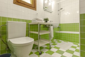 Un baño con inodoro, lavamanos, ducha y piso a cuadros verde y blanco.