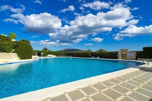 Una piscina azul cristalina con sillas de descanso y una torre de salvavidas.