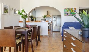 Una cocina moderna con comedor, un sofá azul y una planta grande.