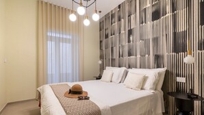 Ein Hotelzimmer mit einem großen Bett, einem Nachttisch, einer Wandlampe und einem Fenster mit Vorhängen.
