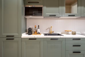 Une cuisine dotée d’un four encastré, d’un évier avec un robinet doré et d’un plan de travail orné de bouteilles de vin et de verres.