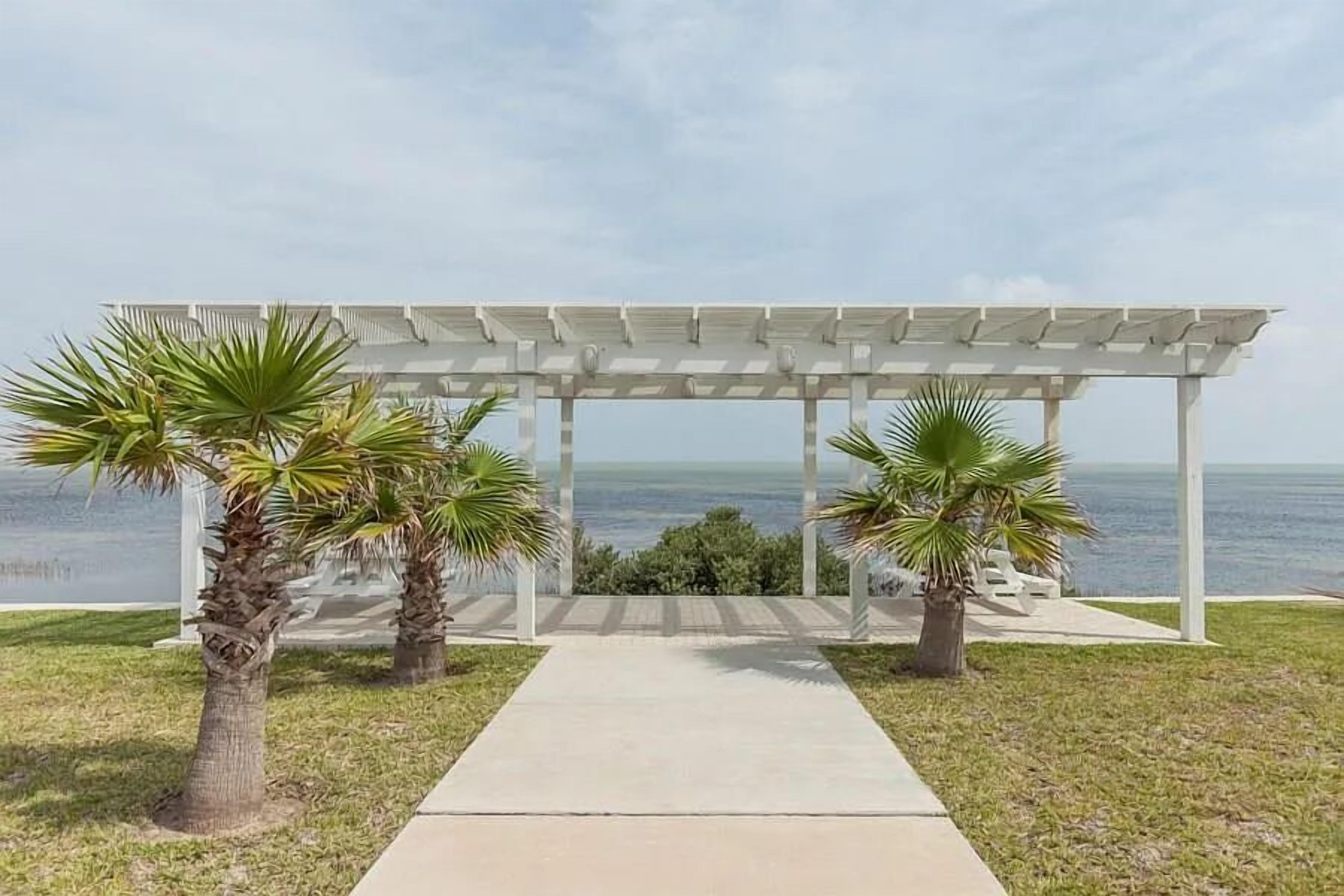 A covered outdoor area with a concrete pathway leading to a view of the ocean.