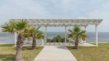 A covered outdoor area with a concrete pathway leading to a view of the ocean.