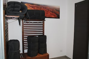 Quarto com um banco de madeira, um suporte na parede e uma pintura de uma floresta.