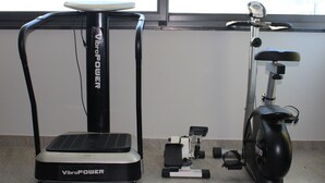 Una habitación con una bicicleta estática y una cinta de correr, ambas con la etiqueta 'VibroPower', y una ventana al fondo.