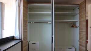 Un armario vestidor con puertas correderas, una barra para colgar ropa y una pequeña zona de escritorio.