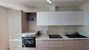 Una cocina moderna con armarios blancos, un horno Bosch, un lavamanos y una encimera con un tostador.