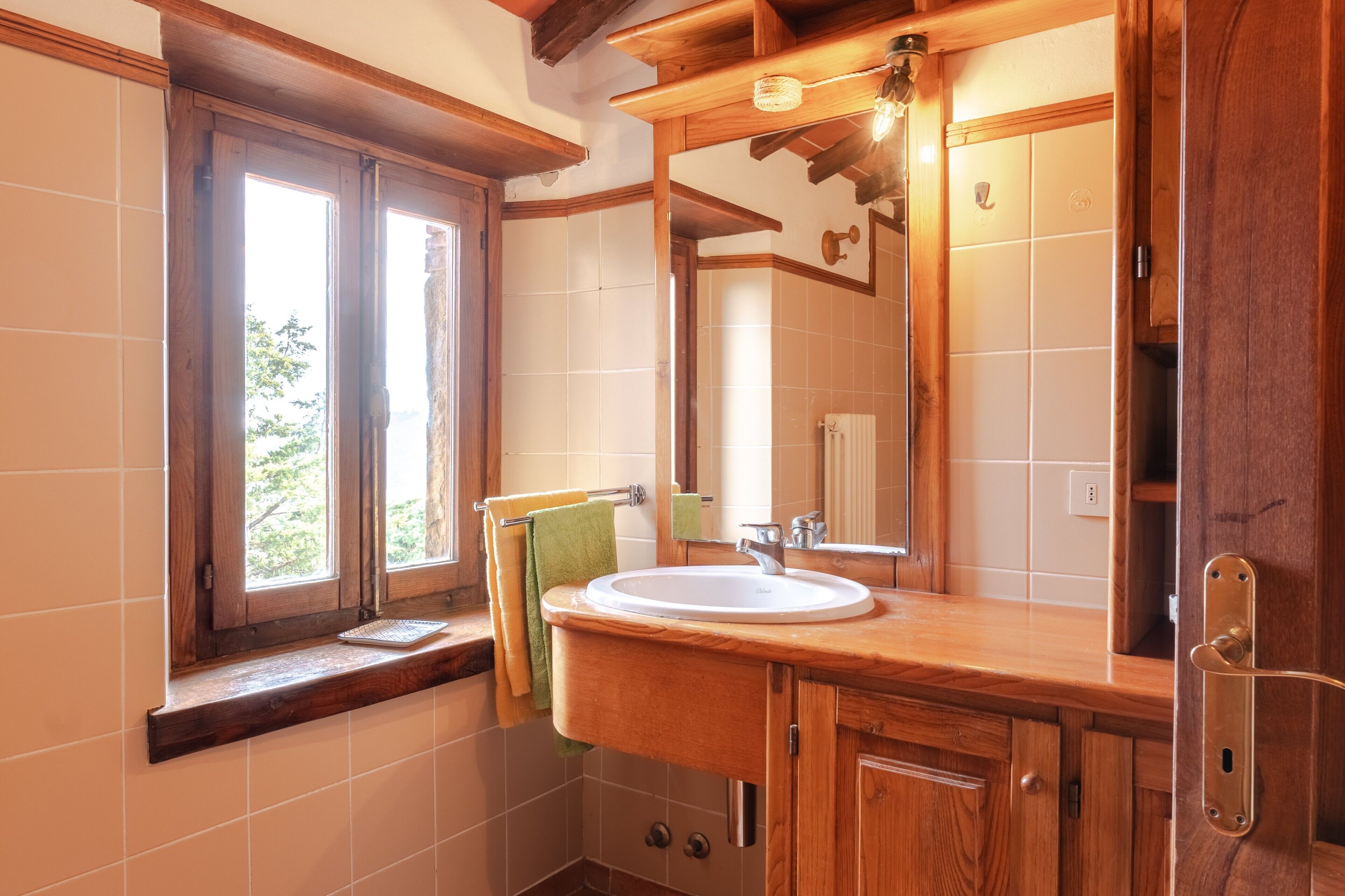 A bathroom with a wooden vanity, a sink, a mirror, and a window.