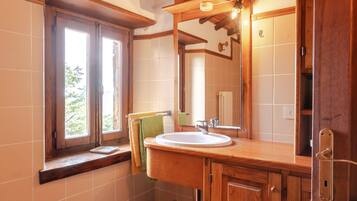 A bathroom with a wooden vanity, a sink, a mirror, and a window.