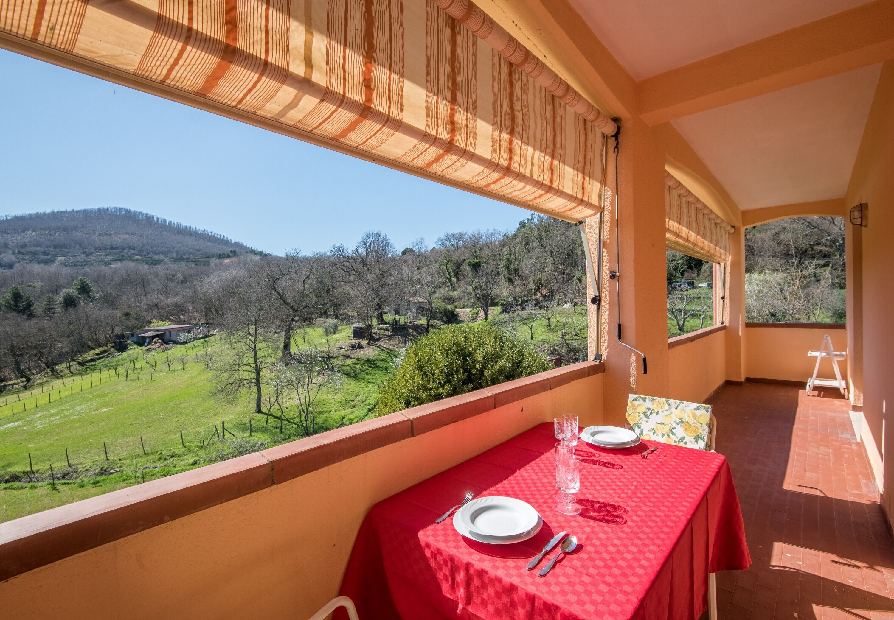 A dining area with a table set for two, overlooking a scenic landscape.