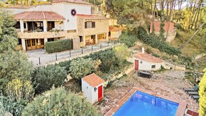 Une villa avec piscine, entourée d’une végétation luxuriante et d’arbres.