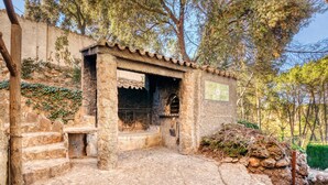 Un bâtiment en pierre avec un toit recouvert de tuiles, des marches menant à l’entrée et une enseigne sur le mur.