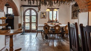 A rustic dining area with a brick archway, wooden chairs, a table with a basket, and hanging greenery. - Apartment 'Reggioli- Appartamento Falegname' with Mountain View, Shared Garden and Balcony (Gaiole in chianti)