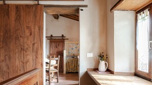 A wooden interior with a kitchen area, a dining table, and a window with curtains. - Apartment 'Reggioli- Appartamento Falegname' with Mountain View, Shared Garden and Balcony (Gaiole in chianti)
