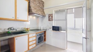 A kitchen with a stove, sink, and microwave. - Apartment 'Matinhos House' with Balcony, Wi-Fi and Air Conditioning (Faro)