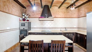 A kitchen with a central island, dark wooden cabinets, a tiled backsplash, and a hanging light fixture. - Holiday Home "Villa Mami - families only" with Private Mini Pool, 2 Private Terraces and Wi-Fi (Chiclana de la frontera)