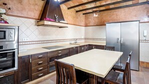 A kitchen with wooden cabinets, a stainless steel refrigerator, a built-in oven, and a dining table with chairs. - Holiday Home "Villa Mami - families only" with Private Mini Pool, 2 Private Terraces and Wi-Fi (Chiclana de la frontera)