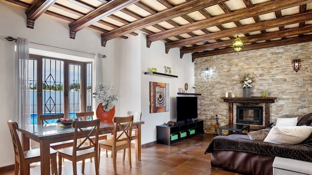 A living room with a dining area, stone fireplace, and a view of the outdoors. - Holiday Home "Villa Mami - families only" with Private Mini Pool, 2 Private Terraces and Wi-Fi (Chiclana de la frontera)