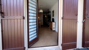 A hallway with wooden doors, a kitchen area, and a dining table. - Studio '4 Personnes Ax3domaines 20' (4 people) (Ax-les-Thermes)