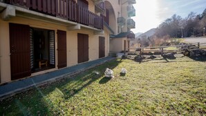 A building with multiple balconies, a grassy area with rocks, and a clear sky. - Studio "Cabine Ax Les 3 Domaines" in a Quiet Setting Near the Slopes (Ax-les-Thermes)