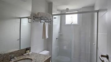 Un baño moderno con encimera de granito, inodoro blanco y ducha con mampara de vidrio.