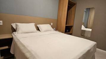 Un dormitorio moderno con una cama grande, un armario de madera y un espejo en la pared.