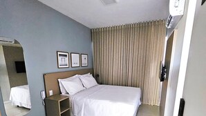 Ein Hotelzimmer mit Bett, Schreibtisch, Spiegel, Nachttisch und einer Tür.