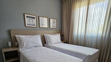 Une chambre d’hôtel avec deux lits, une table de chevet et une fenêtre avec des rideaux.