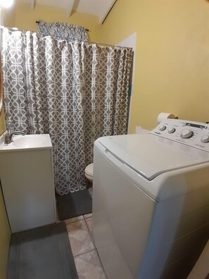 A compact laundry room with a washing machine, a small sink, and a toilet. - Upstairs 2 bedroom (Castries)
