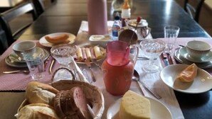A dining table set with various food items and tableware, including bread, cheese, and a pie.