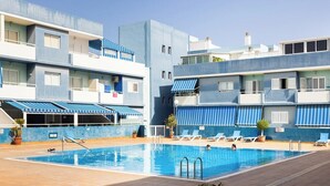 En swimmingpool med liggestole og en bygning med balkoner.