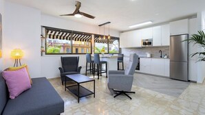 Eine moderne Küche mit weißen Schränken, einem Edelstahl-Kühlschrank und einem Essbereich mit einer Couch und Stühlen.