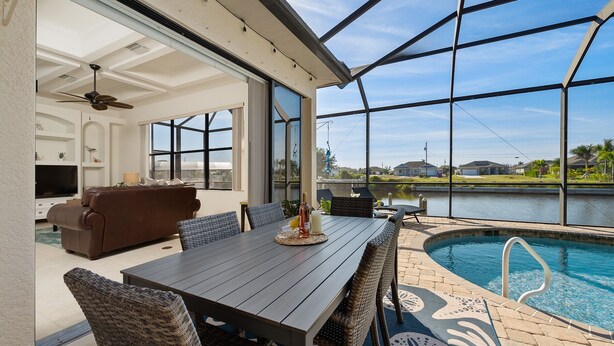 Ein überdachter Patio-Bereich mit Pool, Esstisch und Sofa.
