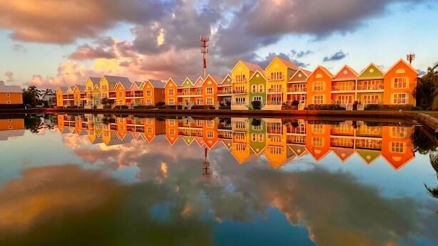 Una hilera de casas coloridas reflejándose en aguas tranquilas, con un cielo nublado arriba.